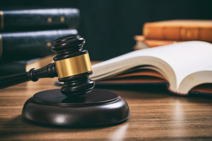 judge-gavel-on-a-wooden-desk-law-books-background-PAKUPF2-700x466 